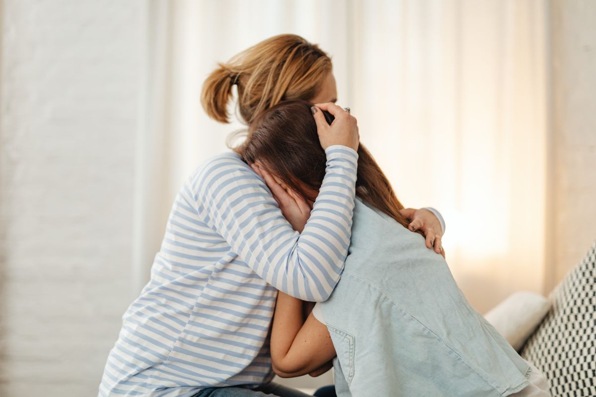 Mãe consolando filha adolescente em luto